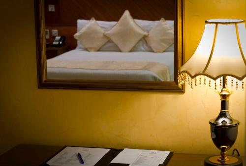 a bedroom with a bed with a mirror and a lamp at Palace Hotel Arusha in Arusha
