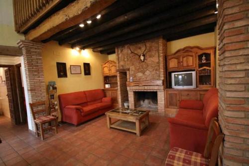 a living room with red couches and a fireplace at Casa Rural Finca El Tornero in Aracena