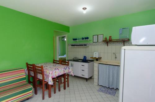 a kitchen with green walls and a table and chairs at Pousada Recanto Dom Arthur in Itapema