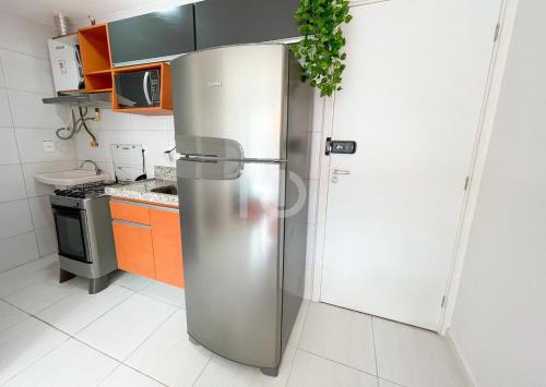 una nevera de acero inoxidable en una cocina con armarios naranjas en PORTO DE GALINHAS- Muro Alto Condomínio Clube-B03, en Ipojuca