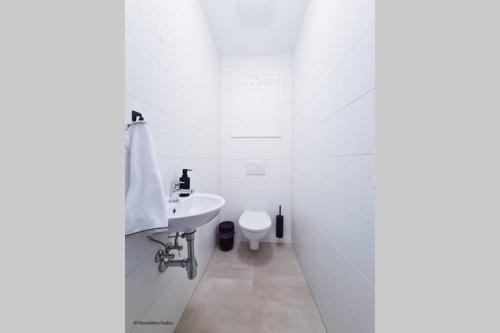a white bathroom with a sink and a toilet at Friendship Suite in Mörbisch am See