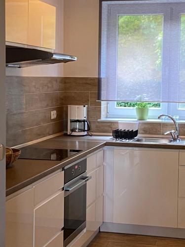 a kitchen with white cabinets and a sink and a window at Lesny Apartament in Ostrzyce