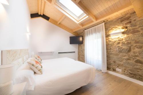 a bedroom with a white bed and a stone wall at Landras de Compostela in Santiago de Compostela