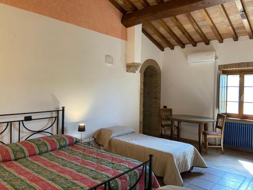 a bedroom with two beds and a table and a window at Bed & Breakfast Casale Gregoriano and Apartaments in San Gimignano