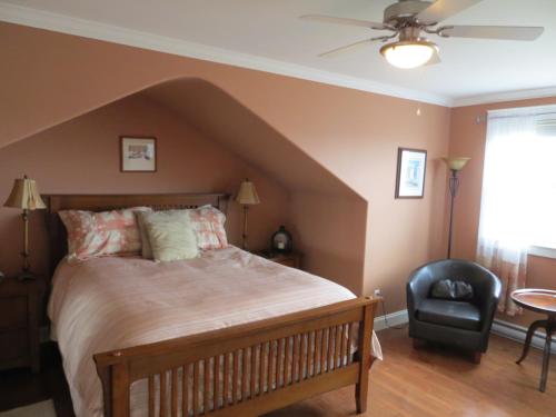 a bedroom with a large bed and a chair at Lancaster Inn B&B in Bonavista