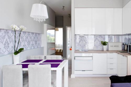 a kitchen with white cabinets and a purple table and chairs at Sunny Stay Apartment in Świnoujście