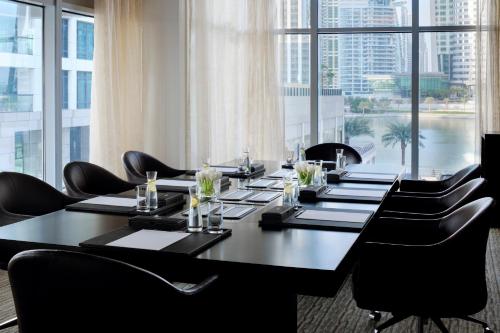 a conference room with a long table and black chairs at Mövenpick Hotel Jumeirah Lakes Towers Dubai in Dubai
