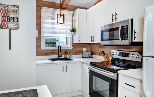 a kitchen with white cabinets and a stove top oven at Condo 47 Chemin de la Corniche by Les Chalets Alpins in Stoneham