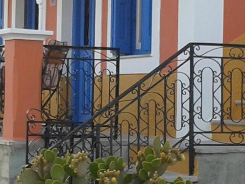a wrought iron balcony with a blue window and a cactus at Nikolitsi Studios in Symi