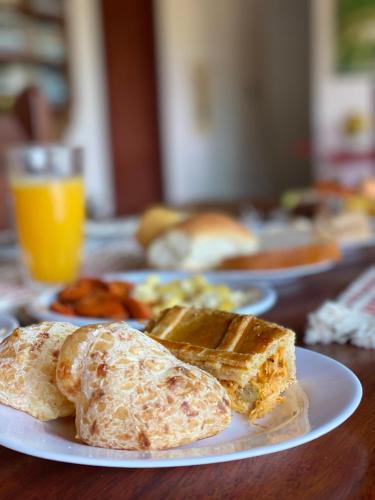 two plates of breakfast food on a wooden table at Pousada e Chalés Arco-Íris in Lima Duarte