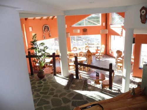 sala de estar con paredes de color naranja, mesa y sillas en Hosteria del Sauquen, en Caviahue