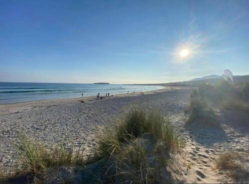 a beach with people walking on the sand and the ocean at Ross Beach Family Farmhouse B&B in Killala