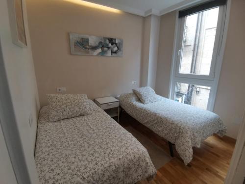 2 camas en una habitación con ventana en Burgas Termal, en Ourense