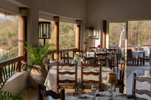 a dining room with tables and chairs and windows at Grand Matlali Suites & Villas Riviera Nayarit in Cruz de Huanacaxtle