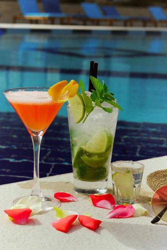 a cocktail and a drink on a table next to a pool at Kraal Hotel Vlore in Vlorë