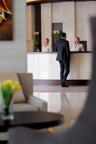 a man in a suit standing in front of a mirror at Mövenpick Hotel Jumeirah Lakes Towers Dubai in Dubai