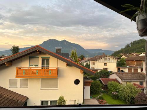 Una casa con balcón con una montaña al fondo. en Roof Heaven Ferienwohnung, en Blaichach