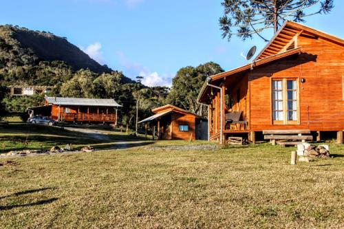 a wooden cabin with a grass field in front of it at Pousada Recanto do Lobo Chalés em Urubici in Urubici