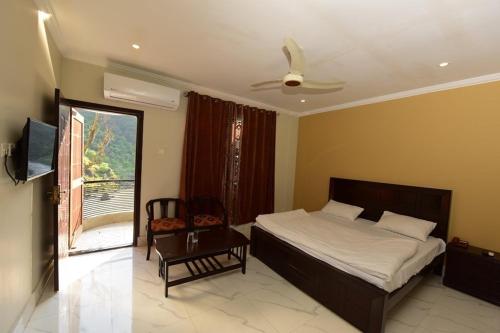 a bedroom with a bed and a chair and a window at Hotel La Orilla Muzaffarabad in Muzaffarabad