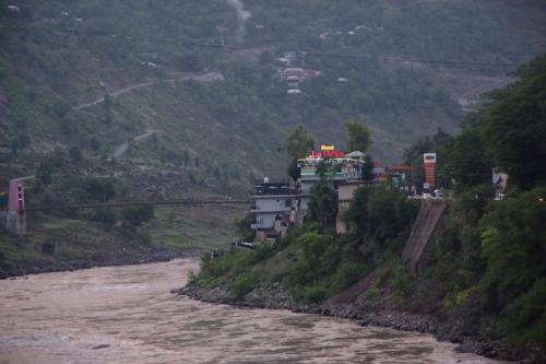 a building on a hill next to a river at Hotel La Orilla Muzaffarabad in Muzaffarabad