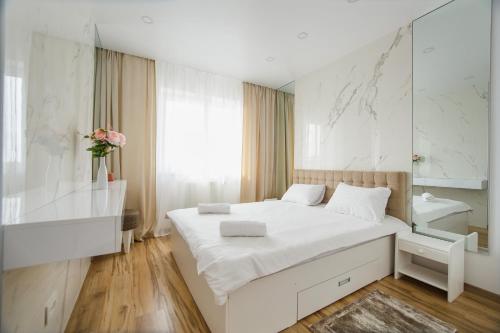 a white bedroom with a large white bed and a mirror at Elegant & Spacious – Central Apartment in Oradea
