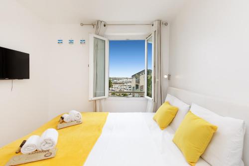 Cette chambre comprend un lit blanc avec des oreillers jaunes et une fenêtre. dans l'établissement Great Sea View YourHostHelper, à Cannes