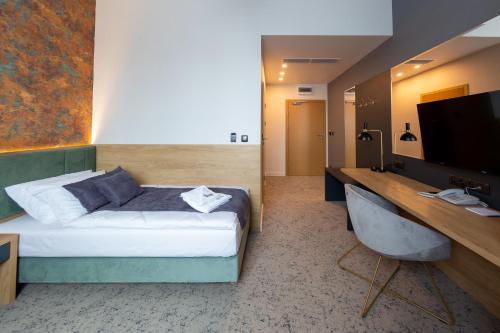 a bedroom with a bed and a desk with a television at Hotel & SPA Hetman in Siedlce