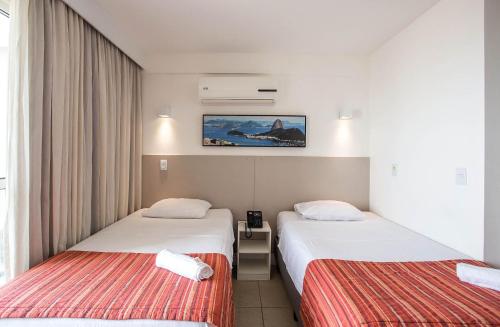 um quarto de hotel com duas camas e uma foto na parede em Flat 1506 - Studio duplo a 600m da Petrobras em Imbetiba em Macaé