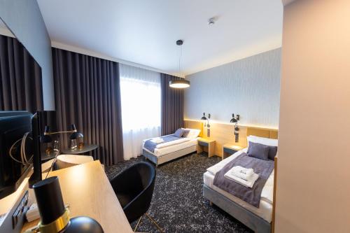 een hotelkamer met 2 bedden en een bureau bij Hotel & SPA Hetman in Siedlce