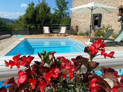 a swimming pool with red flowers in front of it at Chambres d'Hôtes La Bastide St Julien in Anduze