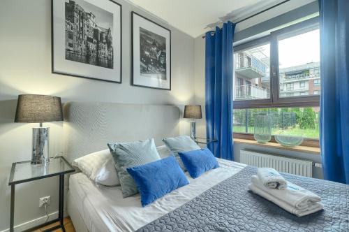 a bedroom with a bed with blue curtains and a window at EXCLUSIVE New Town Apartments in Szczecin