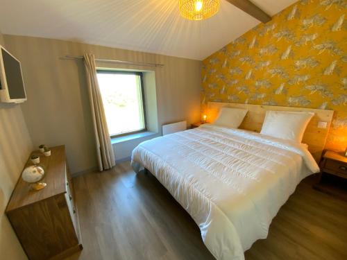 um quarto com uma cama grande e uma parede amarela em La Grange du Damian em Neuville