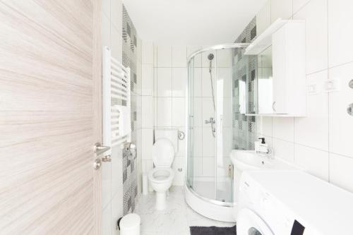 a white bathroom with a toilet and a sink at Djokic Apartments in Kragujevac