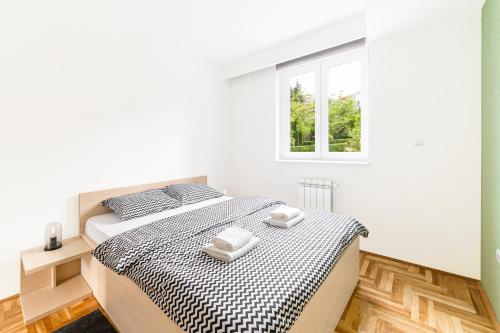 ein weißes Schlafzimmer mit einem Bett und einem Fenster in der Unterkunft Djokic Apartments in Kragujevac