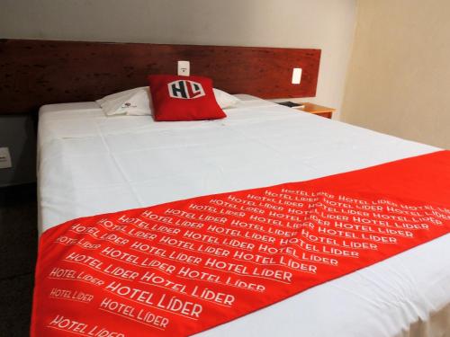 ein rotes Kissen auf einem weißen Bett mit einer roten Decke in der Unterkunft Hotel Líder - By UP Hotel in Timóteo