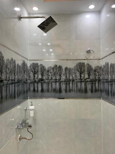 a bathroom with a shower with a painting of trees at pyramids gardens guest house in Cairo