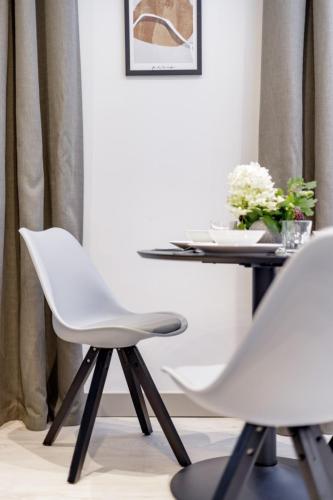 a dining room with a white chair and a table at Apartamenty L11, Limanowskiego in Poznań