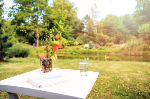 a table with a book and a vase of flowers and a glass at Bed & Breakfast - Warniłęg in Warniłęg