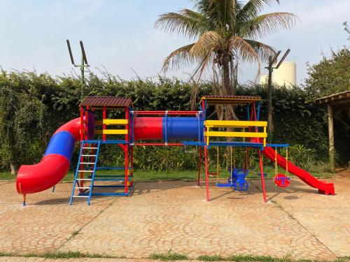 a playground with a slide and a colorful play structure at Hotel Pousada Ourinhos in Ourinhos
