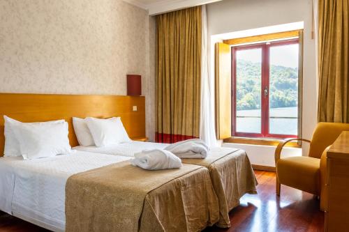 a hotel room with two beds and a window at Douro Hotel Porto Antigo in Cinfães