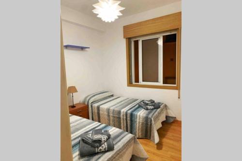 ein Zimmer mit zwei Betten und einem Fenster in der Unterkunft Piso en Portonovo con vistas a la playa in Sanxenxo
