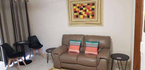 a living room with a brown couch with two pillows at Gold Coast Airport Motel - Only 300 Meters To Airport Terminal in Gold Coast