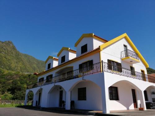 a white building with balconies and a mountain at Casa da Sogra - Apartamento 2 in Faja Grande