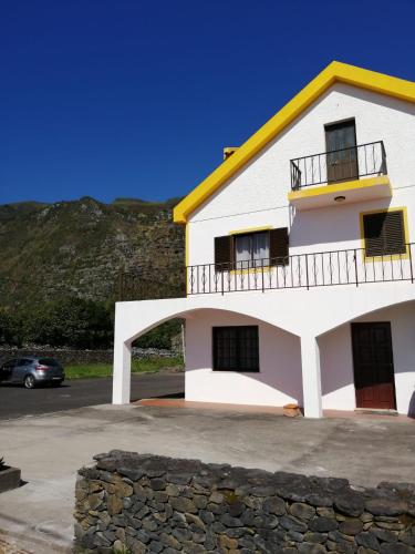 a white and yellow house with a car parked in front at Casa da Sogra - Apartamento 3 in Faja Grande