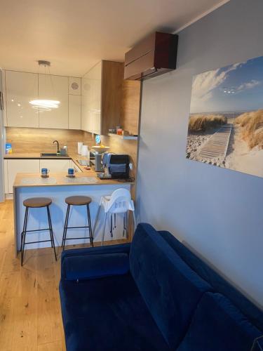 une cuisine avec un canapé bleu et un comptoir de cuisine dans l'établissement Apartament Amber, à Gąski