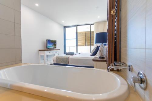 a bathroom with a tub and a bedroom with a bed at 3 Bedroom Ultimate Luxury Waterfront in Cannonvale