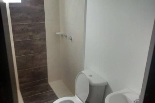 a white bathroom with a toilet and a shower at Apartamento Amoblado 3 hab 2 baños con excelente vista montañas cafeteras acogedor ambiente familiar, piscinas niños adultos, parqueadero, BBQ y ascensor con muy buena iluminación natural in Hojas Anchas