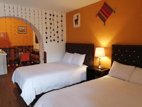 a hotel room with two beds and a table with a lamp at wayra house san blas in Cusco