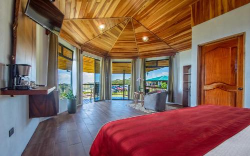 ein Schlafzimmer mit einem großen Bett mit einer roten Tagesdecke in der Unterkunft Hotel Trópico Monteverde in Monteverde Costa Rica