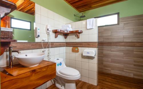 uma casa de banho com um WC branco e um lavatório. em Hotel Trópico Monteverde em Monteverde